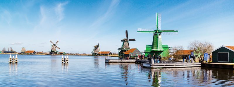 Windmills panorama in Zaanse Schans, North Holland, traditional village, tourists, blue sky